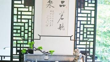 Une pièce de style japonais traditionnel, avec un sol recouvert de tatamis, un paravent en papier de riz (shoji) et un rouleau calligraphié suspendu au mur.