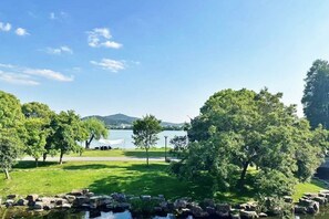 A serene lakeside setting with trees, a clear sky, and a tent in the background.