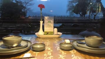 A table set with traditional Chinese tea ceremony utensils, including teapots, cups, and a vase with a flower.