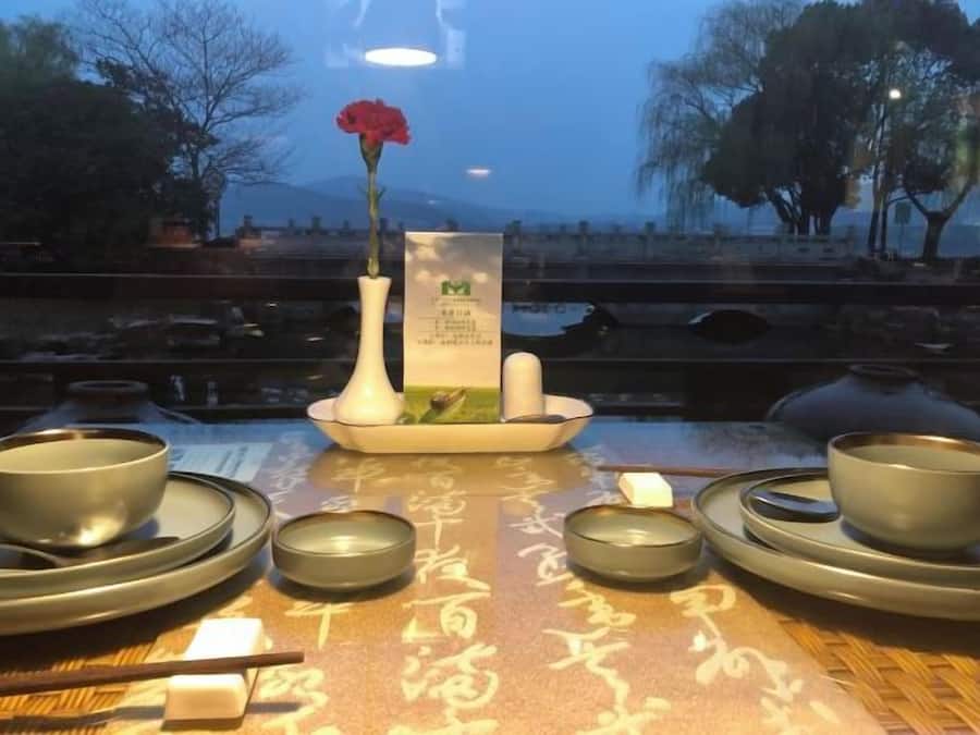 A table set with traditional Chinese tea ceremony utensils, including teapots, cups, and a vase with a flower.