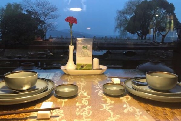 Una mesa dispuesta con utensilios para una ceremonia tradicional del té chino, incluyendo teteras, tazas y un jarrón con una flor.