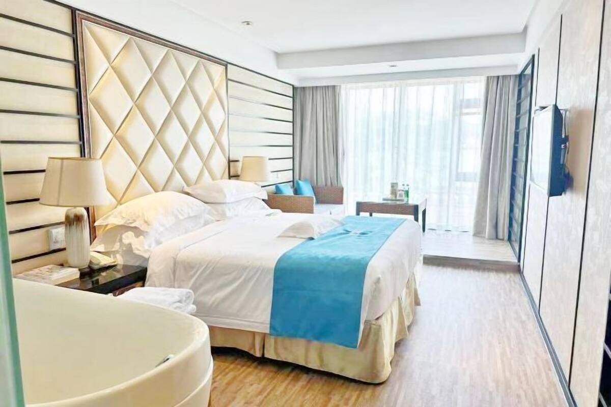 Habitación de hotel con una cama grande, mesitas de noche, un escritorio y vistas al exterior.