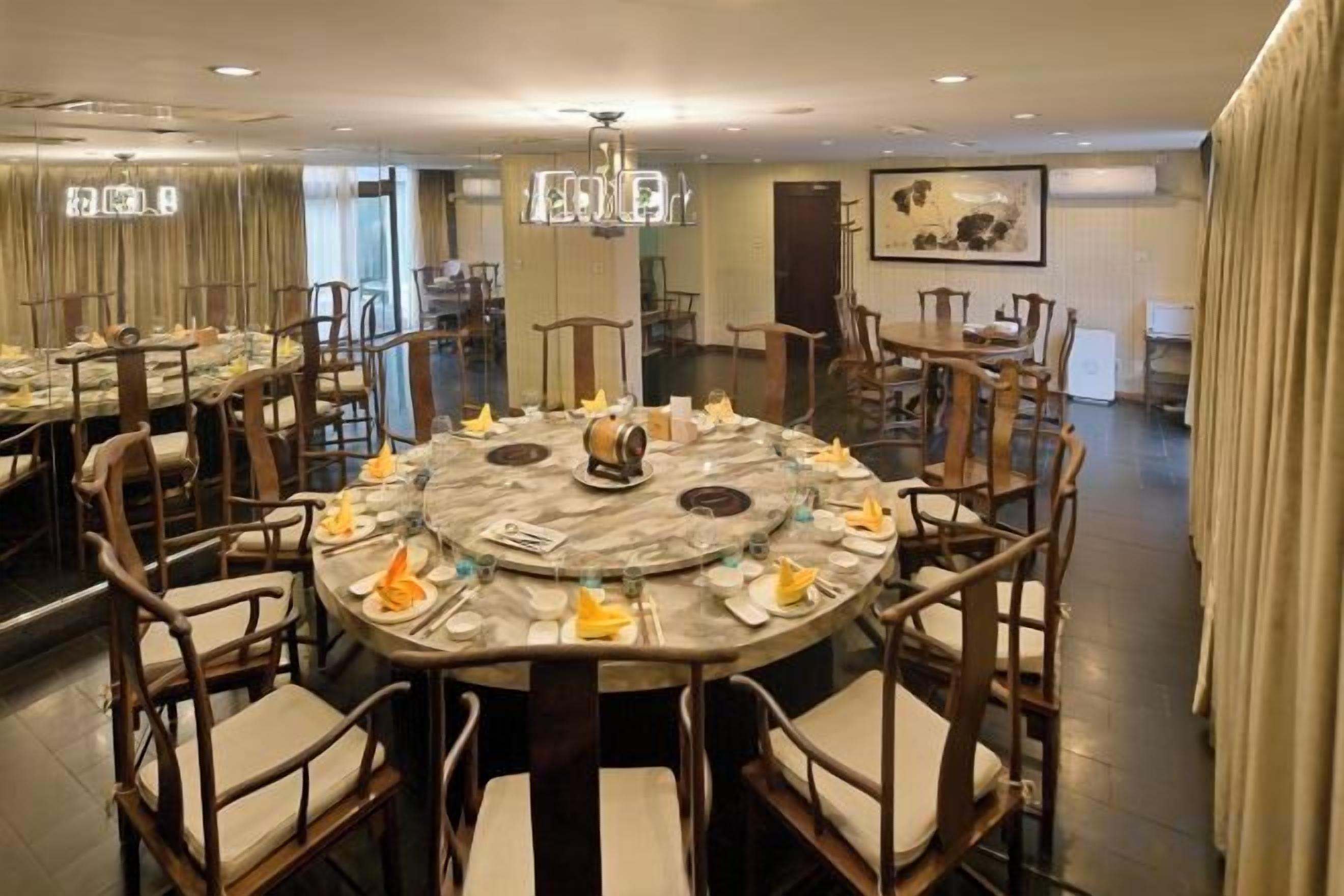 Un comedor de hotel con mesas redondas, sillas y un candelabro.