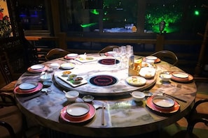 A round dining table set with plates, bowls, and chopsticks, surrounded by chairs. - 1881 Peninsula Hotel (Wuxi)