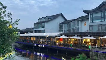 Un edificio a orillas del río con un restaurante en la planta baja, un puente y arquitectura tradicional.