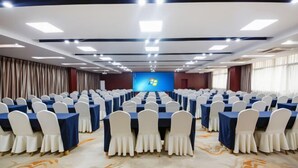 A conference room with rows of tables and chairs, a large screen at the front, and a carpeted floor. - Yinquan Hotel (Shijiazhuang)