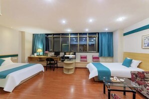 Une chambre d’hôtel avec deux lits, un bureau avec un ordinateur, une chaise et une table basse en verre.