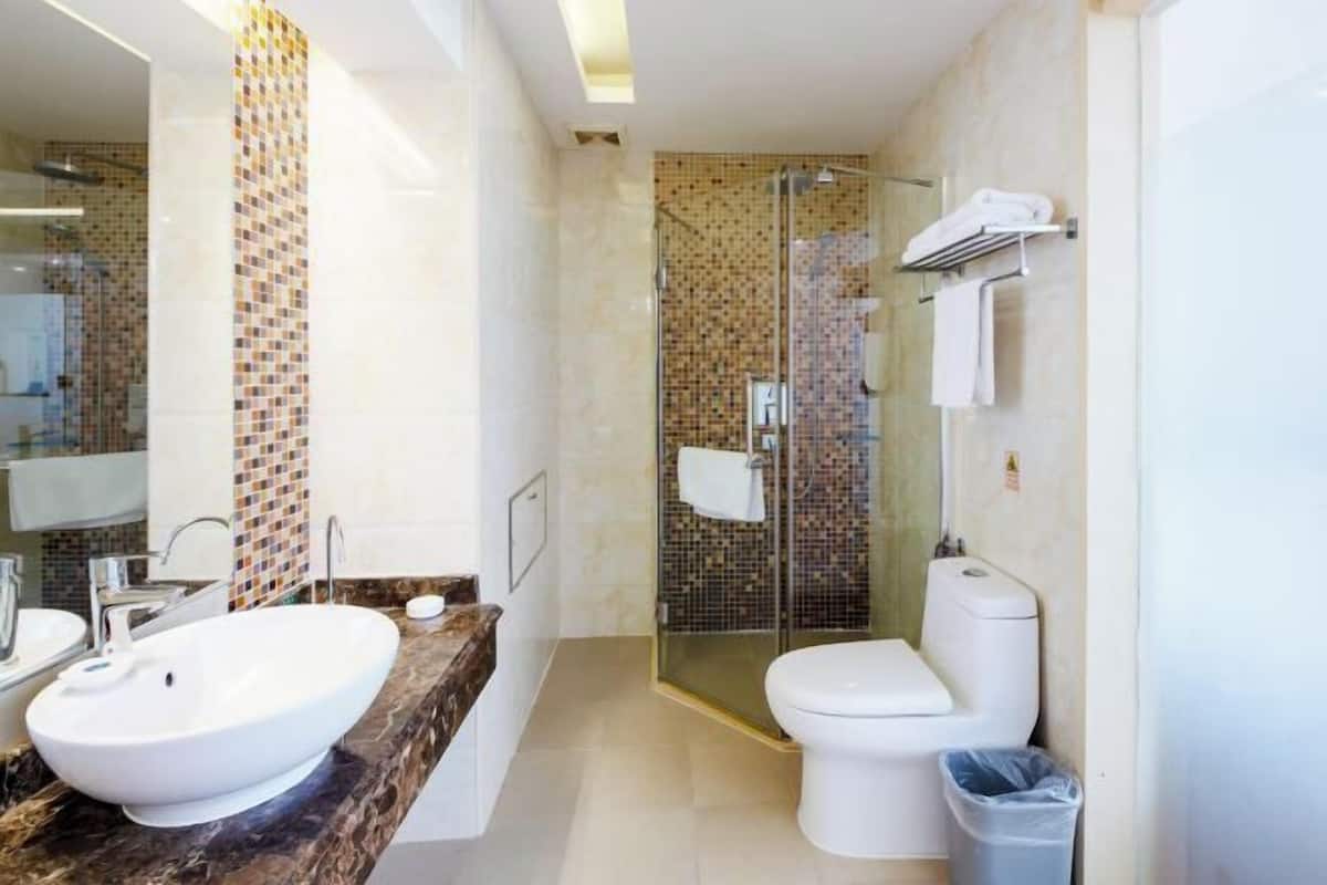 Un baño moderno con un lavamanos grande y blanco, una ducha con mampara de vidrio y un inodoro.