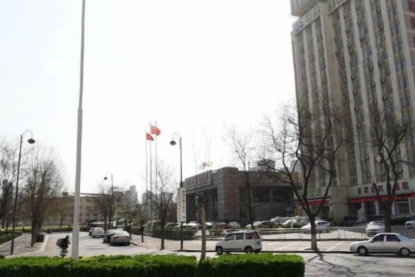 A street view with a tall building, cars, and a flag.