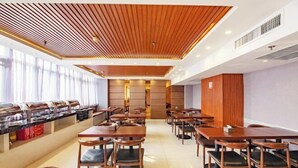 Ein moderner Essbereich mit Holzboden, mehreren Tischen und Stühlen sowie einer Buffettheke.