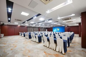 A conference room with rows of tables and chairs, a large screen, and a carpeted floor. - Yinquan Hotel (Shijiazhuang)