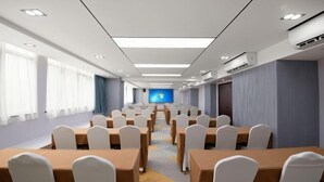 A conference room with rows of tables and chairs, a large screen at the front, and a window on the left side. - Yinquan Hotel (Shijiazhuang)