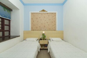A room with two beds, a window with a patterned curtain, a nightstand with a lamp, and a wall with a decorative painting. - Fengju Business Hotel (Hourui Metro Station, Shenzhen Airport) (Shenzhen)
