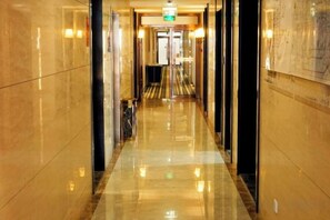 Un pasillo pulido con piso reflectante, que conduce a una puerta al final.