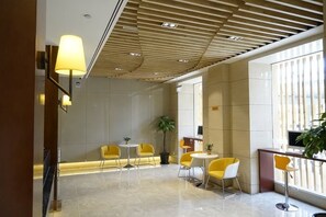 Un hall d’entrée moderne avec un plafond haut, un comptoir d’accueil et des espaces où s’asseoir.