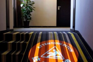 L'entrée d'un hôtel, avec un tapis à rayures et un panneau d'avertissement.