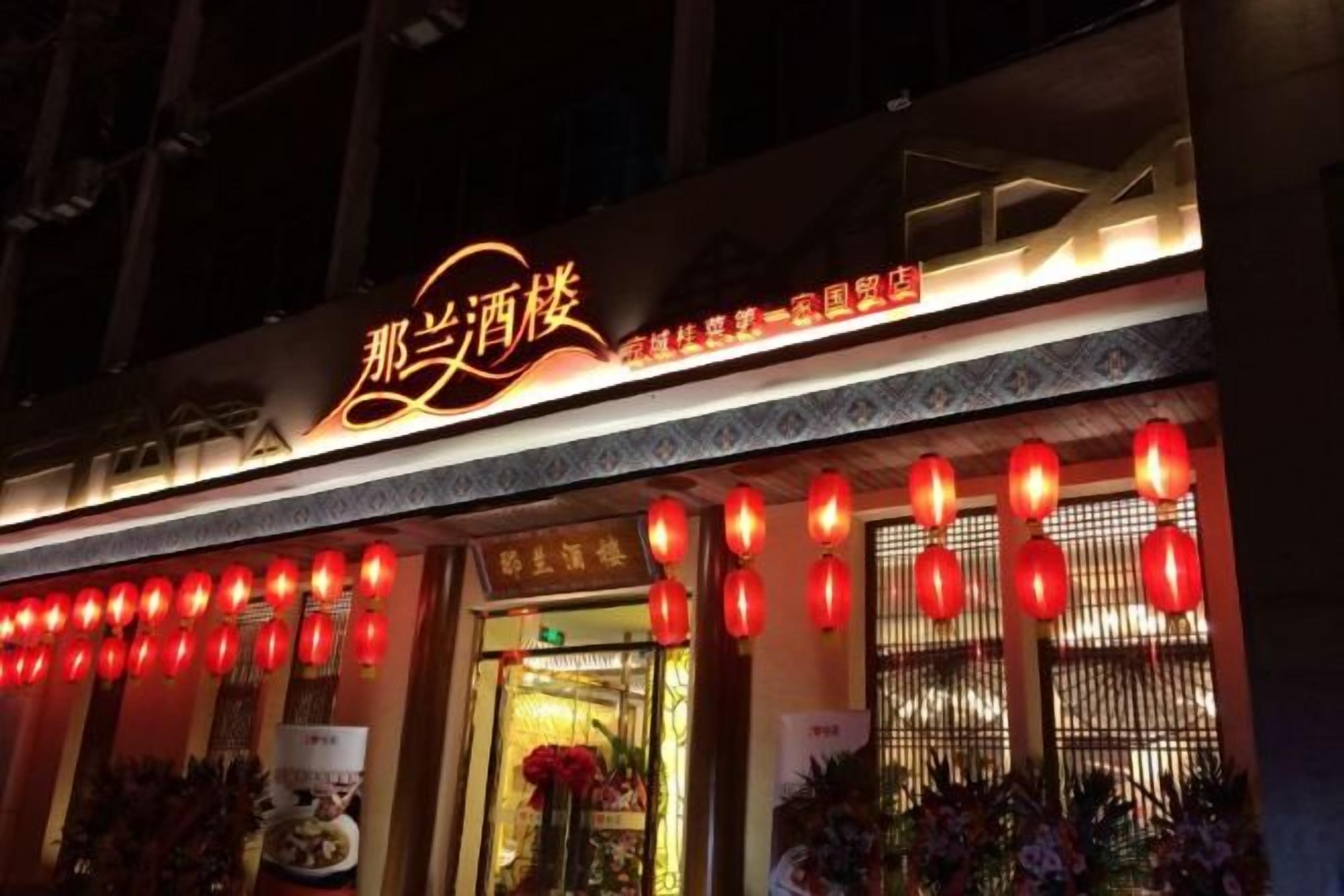 Een restaurant met een neonbord, rode lantaarns en een traditionele ingang.