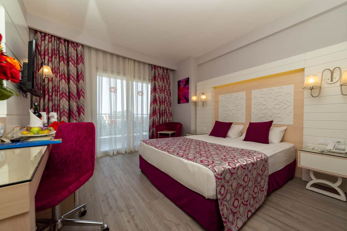 Une chambre d’hôtel avec un lit, un bureau, une chaise et un téléviseur.