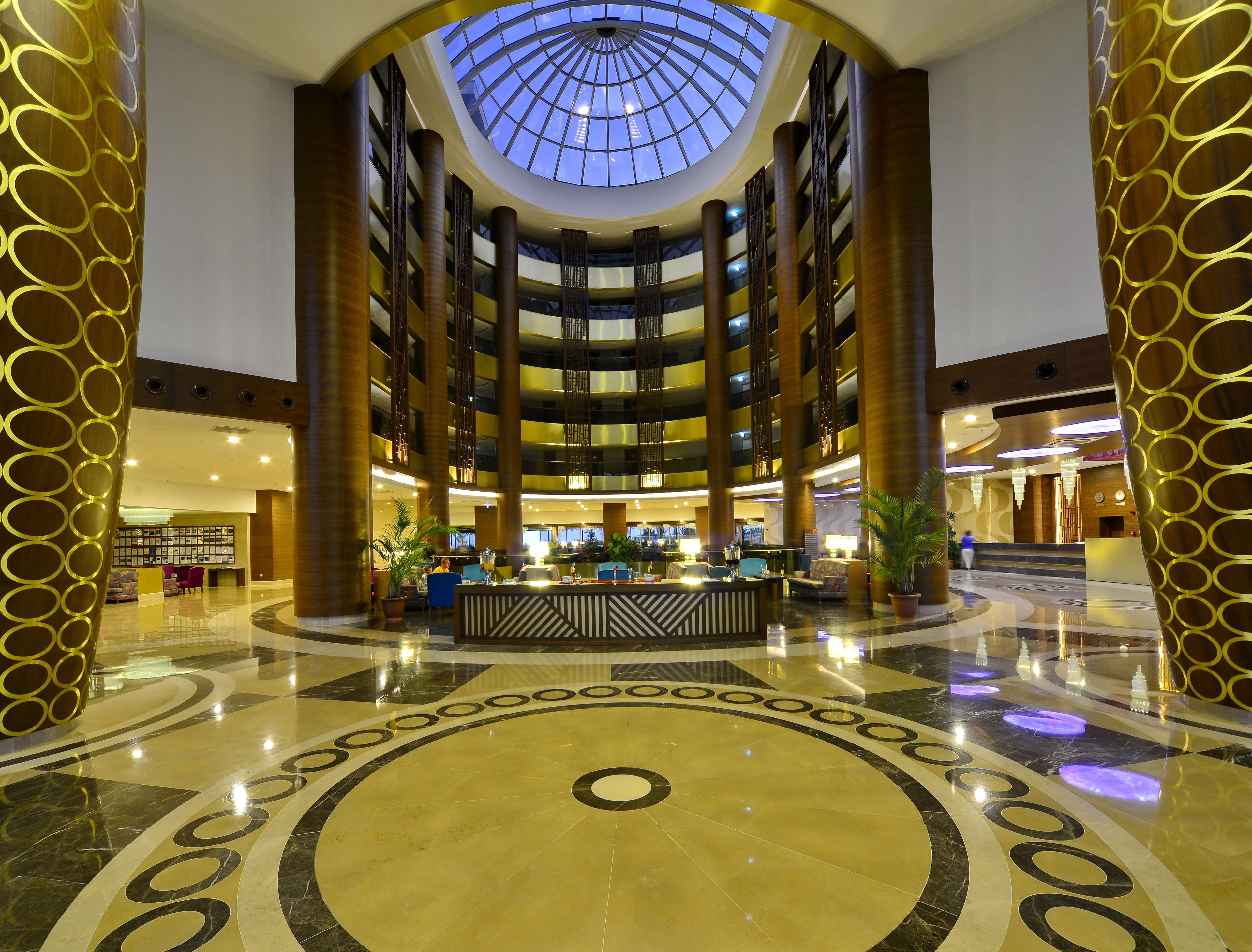 A multi-level atrium with a central open space, multiple floors, and a glass ceiling allowing natural light.