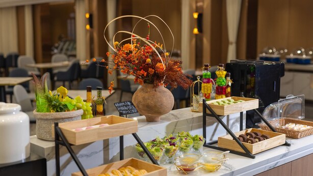 A buffet setup with various food items and a decorative vase. - Days lnn by Wyndham Yantai Penglai (Yantai)