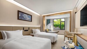 A hotel room with two beds, a desk, a chair, a TV, and a window with a view of greenery. - Days lnn by Wyndham Yantai Penglai (Yantai)