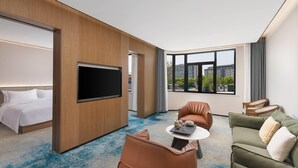 A hotel room with a bed, a TV, a seating area with a table, and large windows. - Days lnn by Wyndham Yantai Penglai (Yantai)