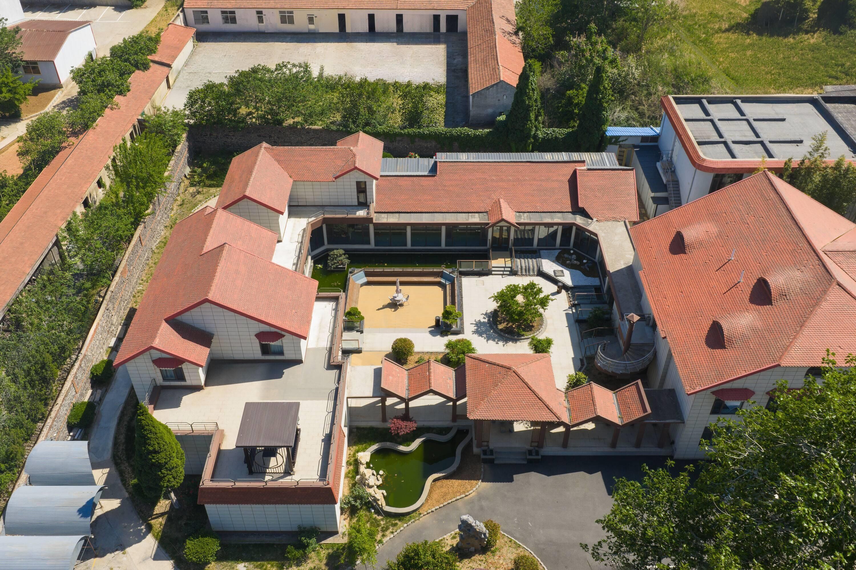 Vista aérea de un complejo residencial con varias edificaciones, un patio central y zonas verdes circundantes.