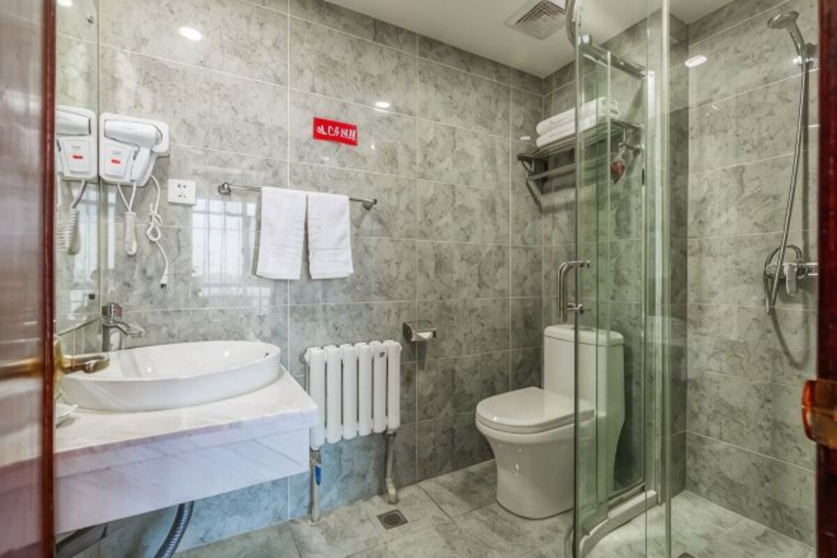 A bathroom with a glass shower enclosure, a white sink, and a toilet.