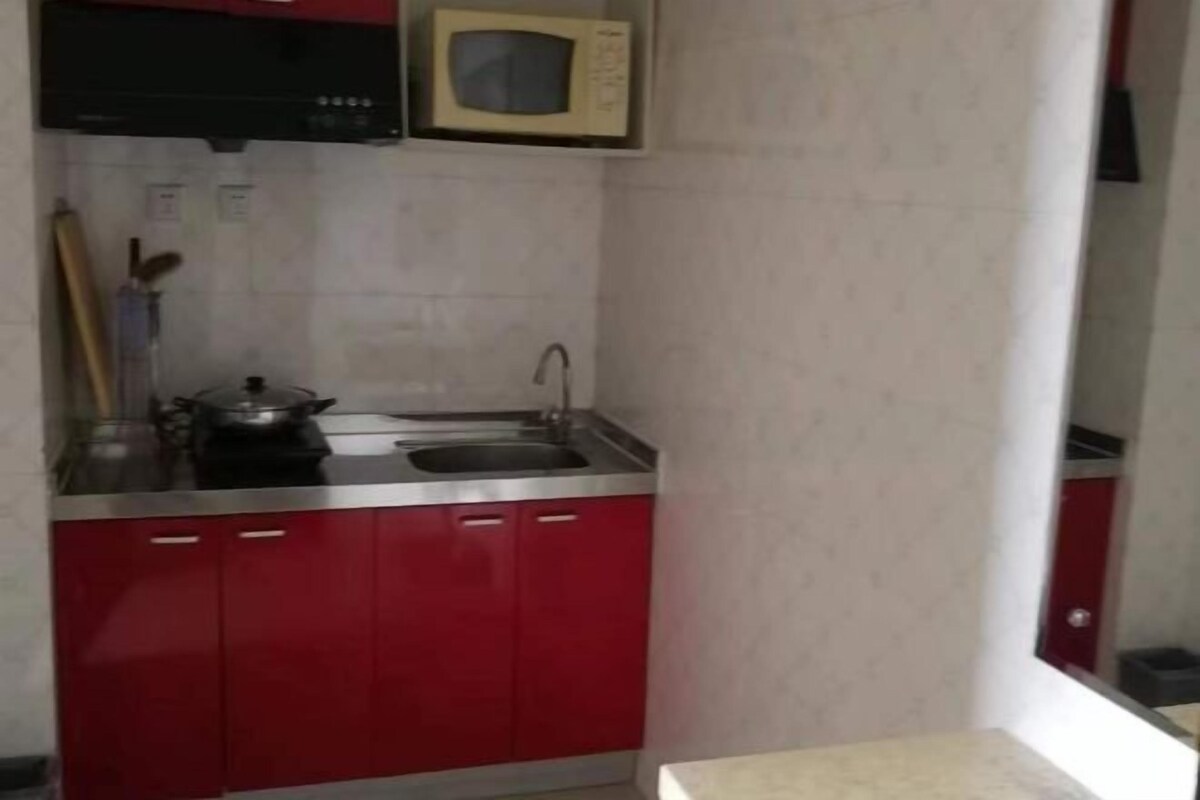 A compact kitchen with red cabinets, a microwave, a sink, and a stove.