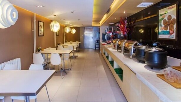 A modern restaurant with a long counter, multiple tables, and hanging lights. - Jinjiang Inn Beijing Zhushikou (Beijing)