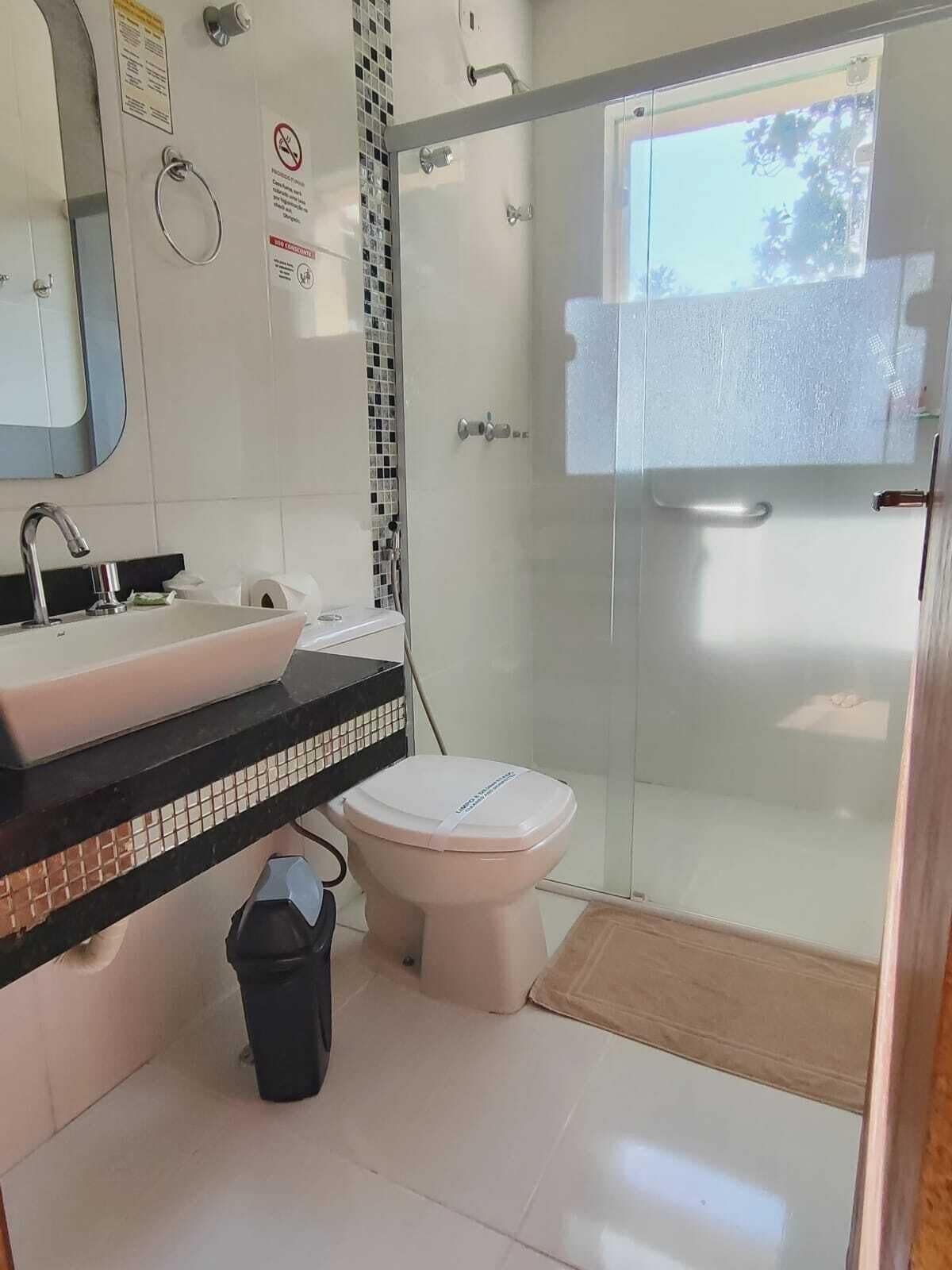 A bathroom with a glass-enclosed shower, a sink with a mirror above it, and a toilet.