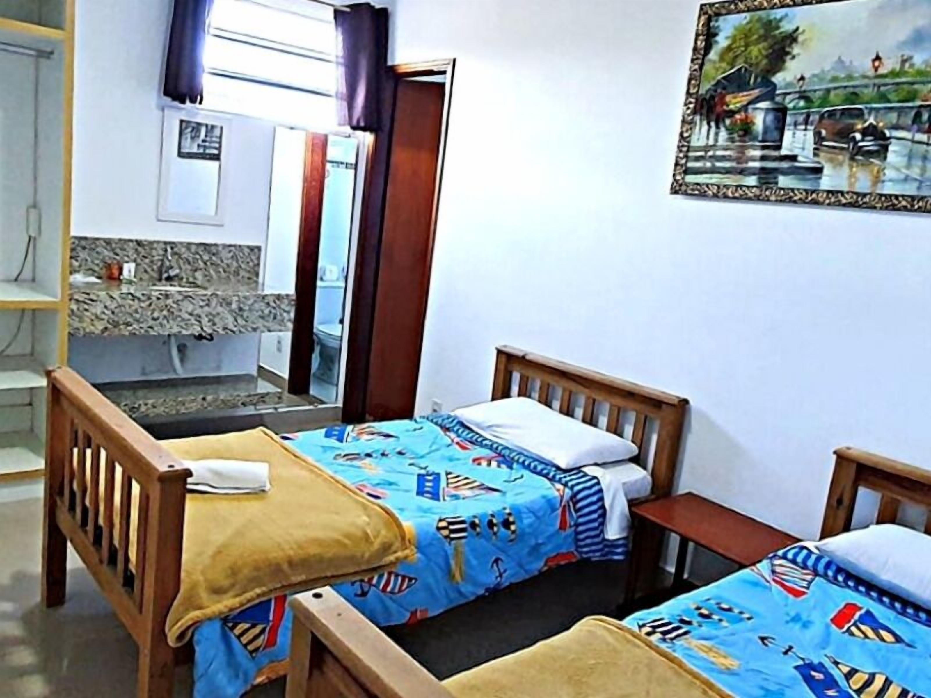 A small room with two wooden beds, a wooden chair, a small table, and a mirror.