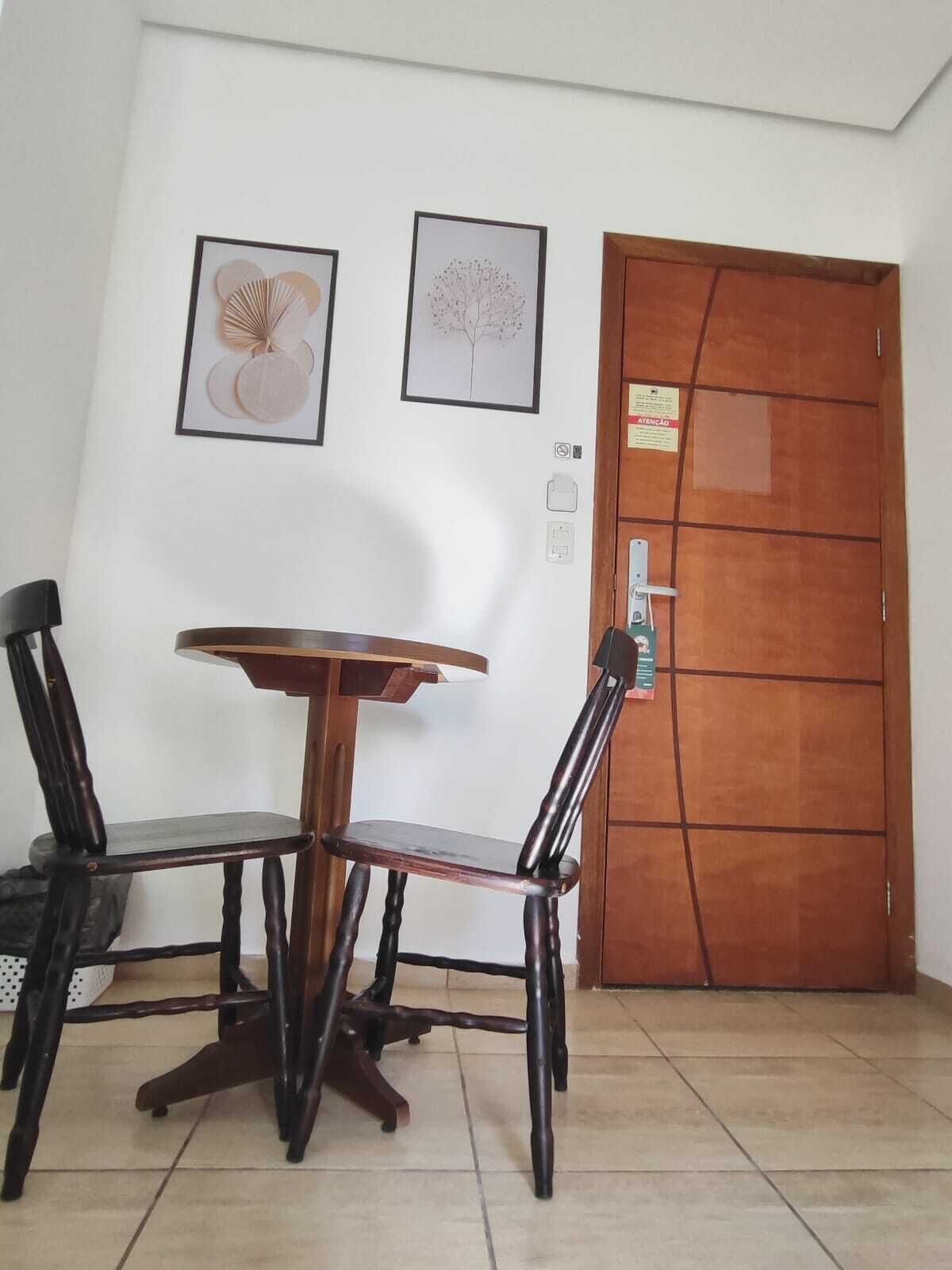 A dining area with a wooden table and chairs, a tiled floor, and a wooden door with a sign.