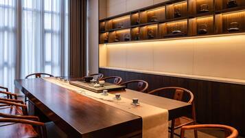 A conference room with a long wooden table, chairs, and a wall-mounted shelf with teapots.
