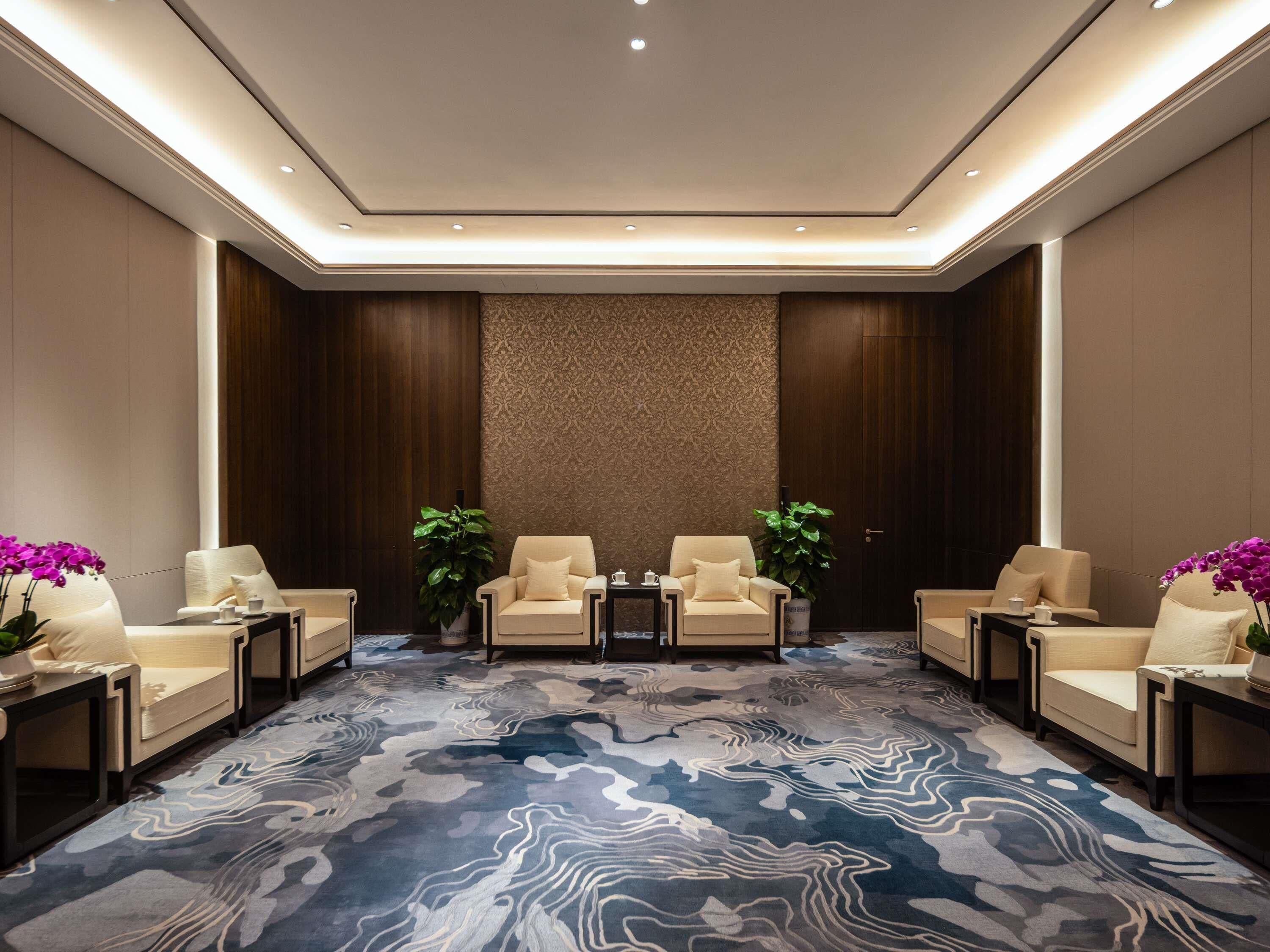 A hotel lobby with a marble-patterned floor, two sofas, and a patterned wall.