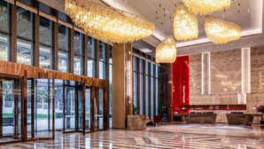 Eine moderne Lobby mit großen Glastüren, einem Empfangsschalter und einer Wand in Rot als Akzent.