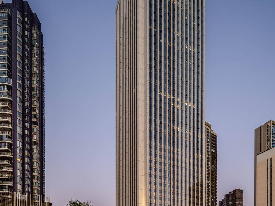 A tall, modern skyscraper with a glass facade, surrounded by other high-rise buildings.
