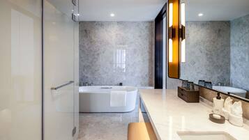 A modern bathroom with a glass shower enclosure, a freestanding bathtub, a vanity with a mirror, and a bench.