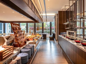 A buffet area with a variety of food items, a seating area, and a view of the outdoors.