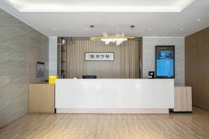 A reception area with a modern design, featuring a reception desk, a wall-mounted digital display, and a ceiling light fixture. - Fanhua Hotel (Shanghai)