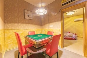 A room with a pool table, red chairs, a framed picture on the wall, and an air conditioning unit.