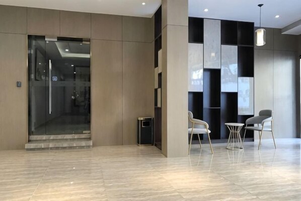 A modern lobby with a glass door entrance, a staircase, and a seating area with two chairs and a small table. - Fanhua Hotel (Shanghai)