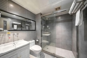 Un baño moderno con ducha de vidrio, lavamanos blanco y un inodoro.