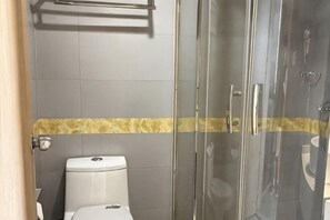 A bathroom with a toilet, a shower with glass doors, and a towel rack. - Fanhua Hotel (Shanghai)