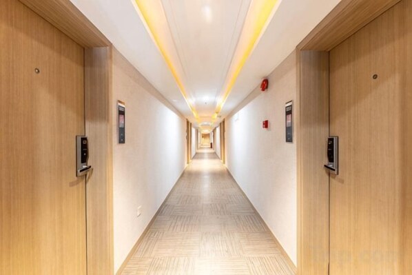 A hotel corridor with wooden doors, a light-colored floor, and a ceiling with recessed lighting. - Fanhua Hotel (Shanghai)