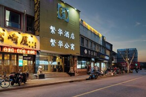 A hotel with a signboard, a storefront with a sign, and a tree in the foreground. - Fanhua Hotel (Shanghai)