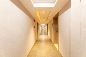A hotel corridor with doors on both sides, a tiled floor, and a ceiling light fixture. - Fanhua Hotel (Shanghai)