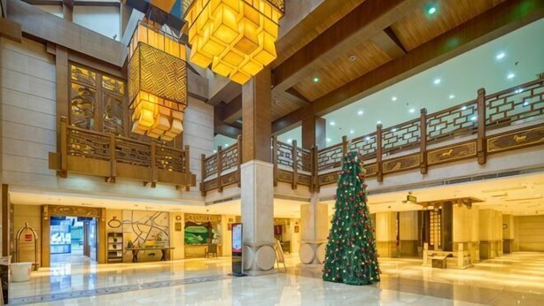 Um hall espaçoso com uma grande árvore de Natal, tetos altos e luminárias geométricas penduradas.