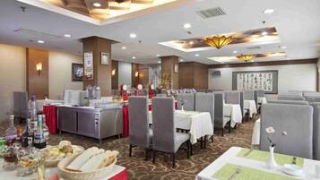Comedor de hotel con varias mesas, sillas y una mesa de buffet.