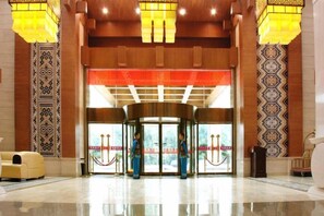 A lobby with a revolving door, a reception desk, and a patterned wall. - Xiangxi National Hotel (Xiangxi)